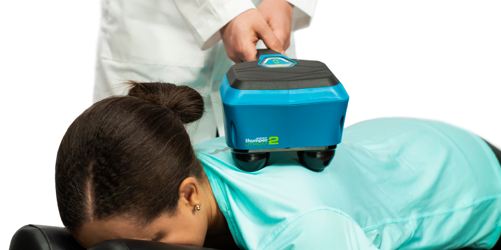 Chiropractor giving a deep tissue back massage in less than 90 seconds. Therapist using Thumper Lithium2 cordless percussion massager on client’s back