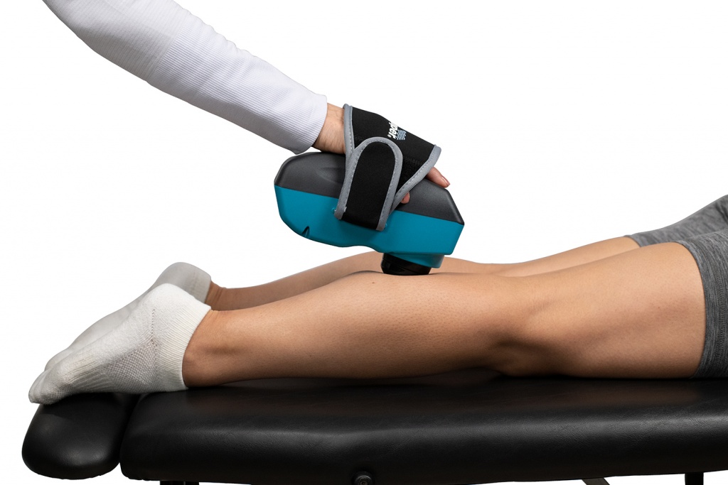 Chiropractor giving a deep tissue back massage on trigger point areas in seconds. Therapist using Thumper Lithium1 cordless percussion massager on client’s leg in clinic